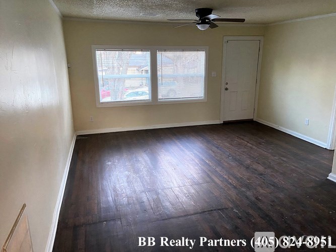 A room with a ceiling fan and wooden flooring.