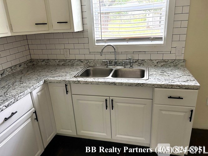 A kitchen with a marble countertop and white cabinets.