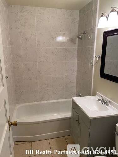 A bathroom with a white tiled shower and a white bathtub.