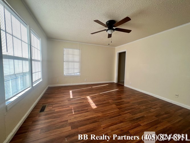 A room with a ceiling fan and wooden flooring.