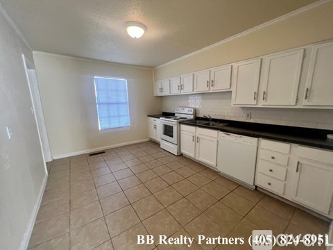 A kitchen with white cabinets and a tiled floor.