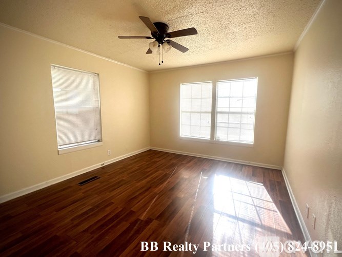 A room with a ceiling fan and two windows.