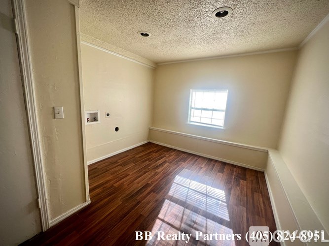 A room with wooden floors and a window letting in sunlight.