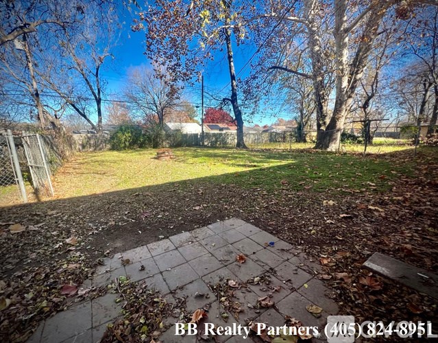 A backyard with a brick patio and trees.