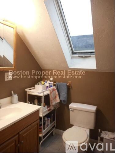 A bathroom with a toilet, sink, and a window.