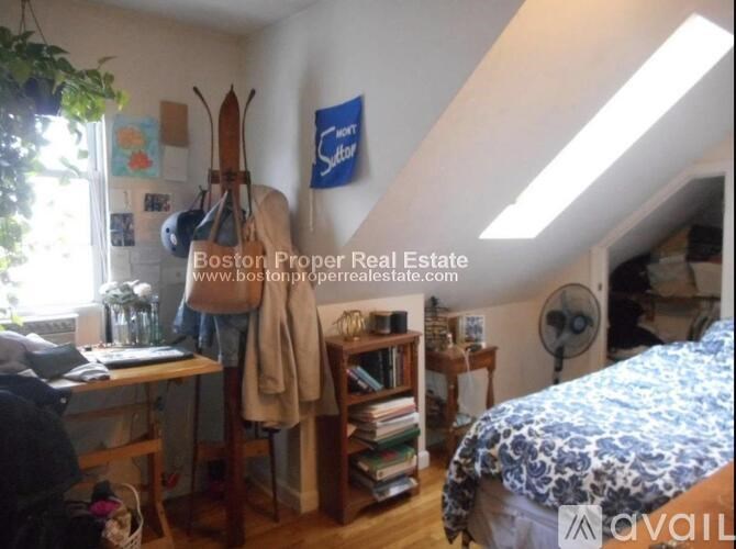 A room with a bed, a desk, and a window with a view of the sky.