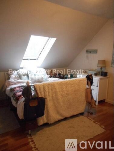 A bedroom with a bed covered in a yellow blanket and a rug on the floor.