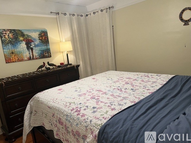 A bedroom with a bed, nightstand, and a painting on the wall.