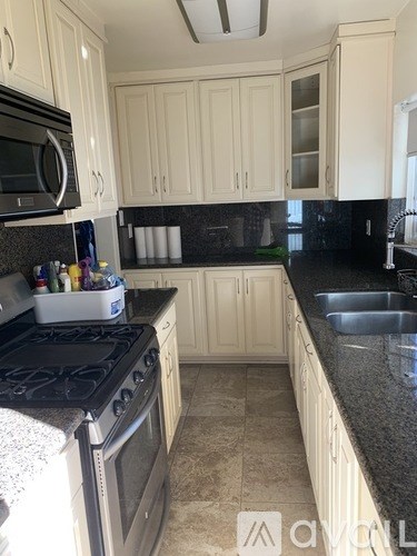A kitchen with white cabinets and black countertops.