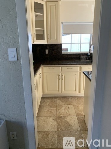 A kitchen with white cabinets and a tiled floor.