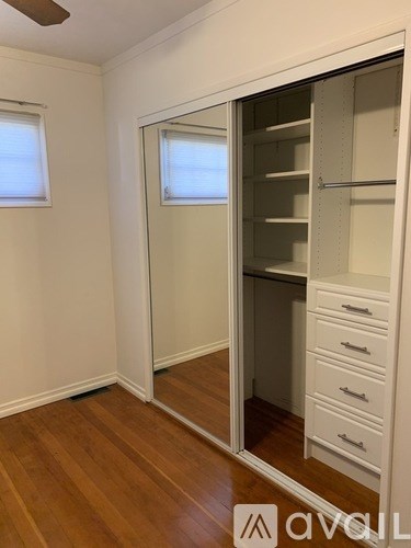 A white closet with a mirror and drawers is open.