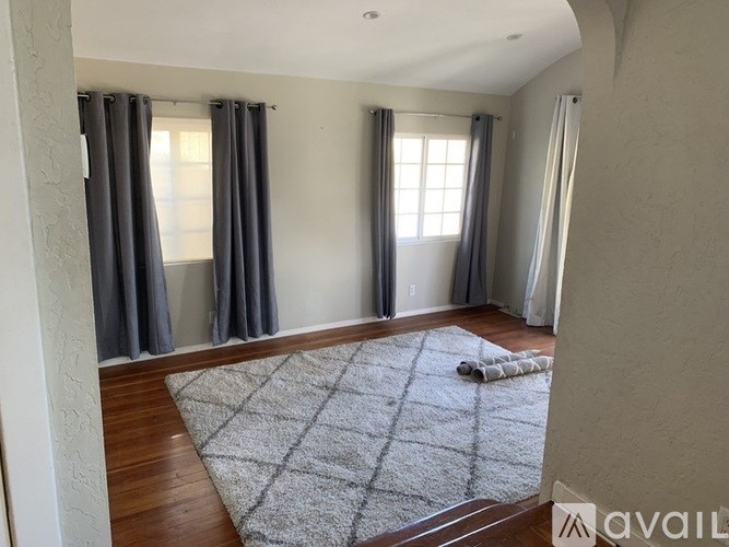 A room with a rug on the floor and curtains on the windows.