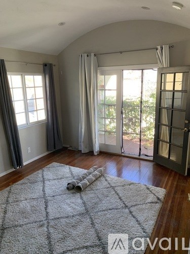 A room with a grey rug and a sliding glass door.