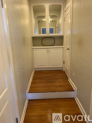 A hallway with a mirrored cabinet and a white door.