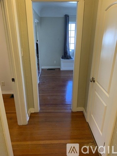 A hallway with wooden floors and white walls.