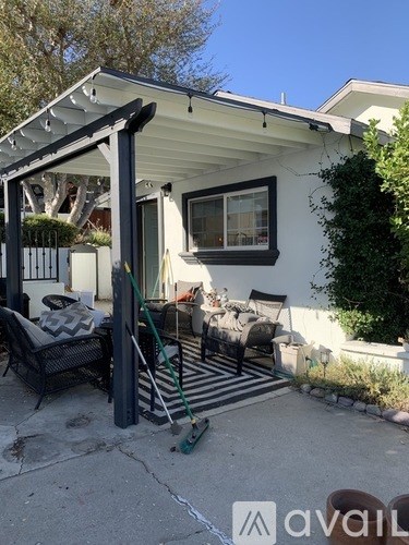 A patio with a black chair and a white house in the background.