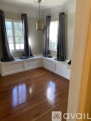 A room with wooden floors and a window with curtains.