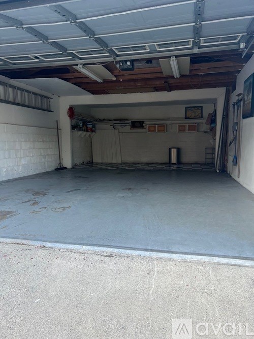 A spacious garage with a white floor and a white ceiling with wooden beams.