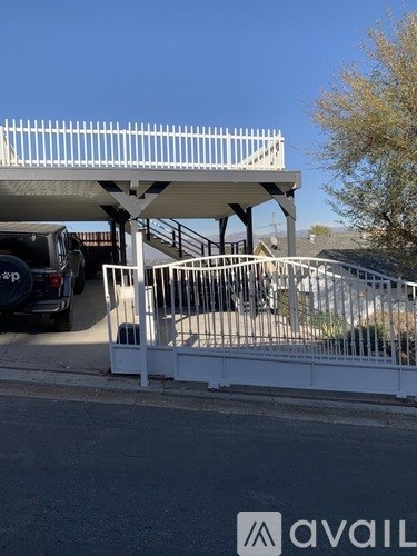 A white metal fence with a car parked behind it.