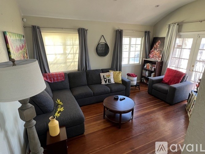A living room with a grey sofa and a wooden floor.