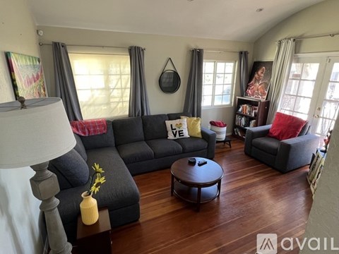 A living room with a grey sofa and a wooden floor.