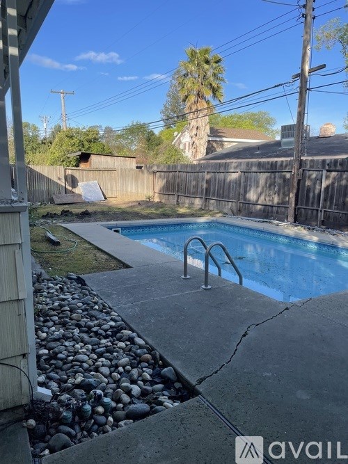 A pool surrounded by a stone wall and a wooden fence.