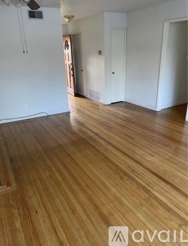 A room with wooden flooring and a door on the left.
