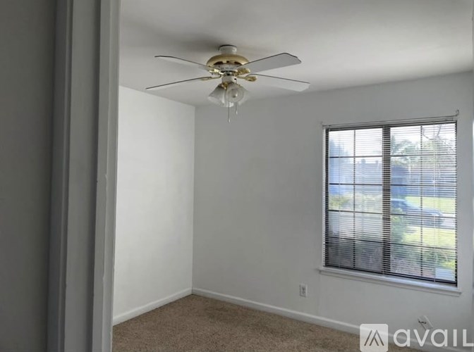 A room with a ceiling fan and a window with blinds.