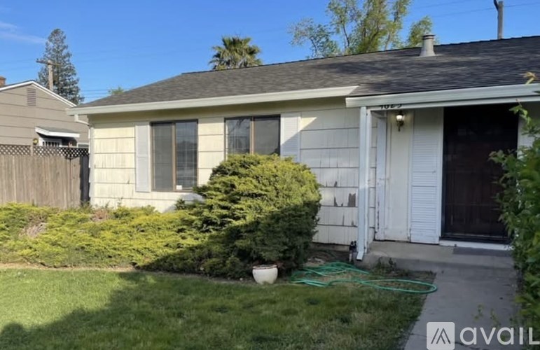 A house with a white door and a green hose on the lawn.