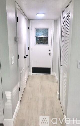 A hallway with a white door and a window.