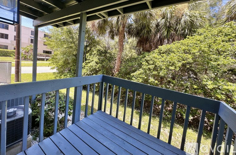 A balcony with a railing and a view of a building and trees.