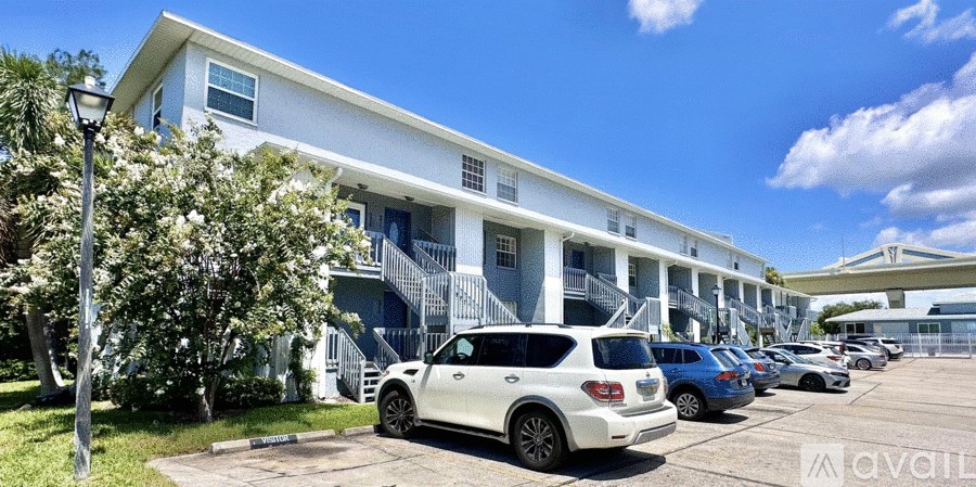 A white car is parked in front of a row of townhouses.