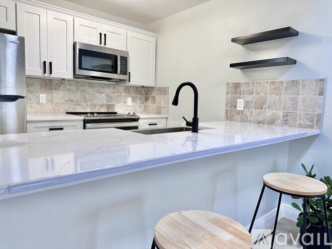 A kitchen with a marble countertop and a black faucet.
