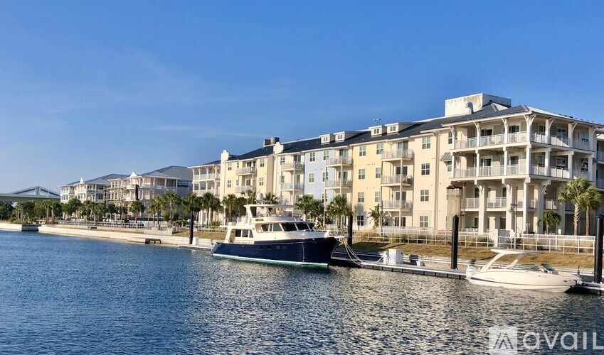 A yacht is docked at a marina in front of a large apartment building.