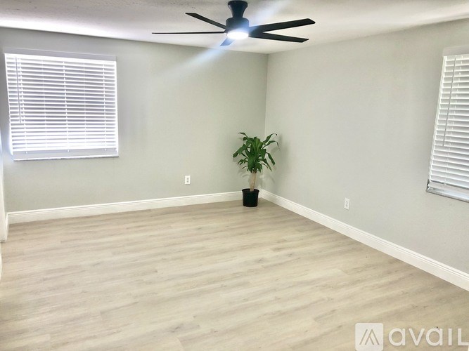 A room with a ceiling fan, a plant, and a window with blinds.
