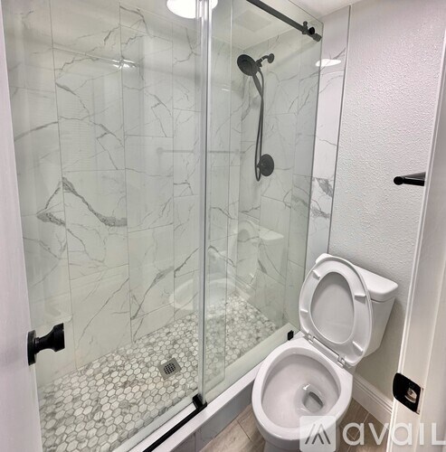 A white toilet in a bathroom with a glass shower door.