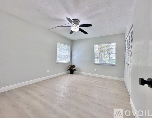 A room with a ceiling fan and two windows.