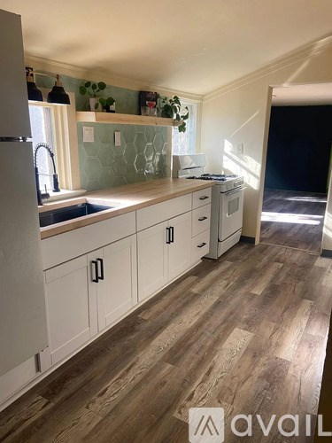 A kitchen with white cabinets and a wooden floor.