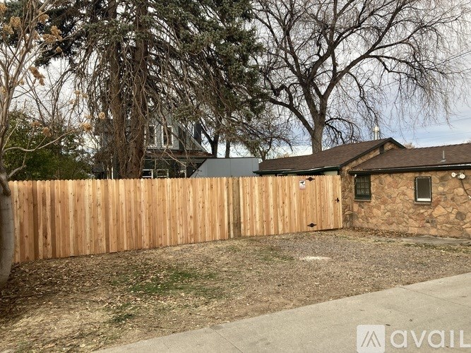 A wooden fence in front of a house with a stone wall.