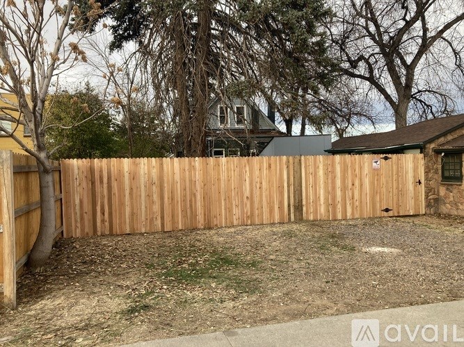 A wooden fence encloses a yard with a house in the background.