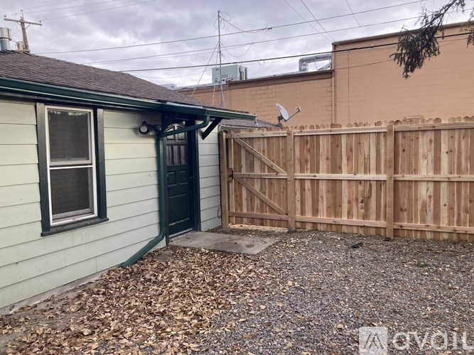 A small house with a green door and a wooden fence.