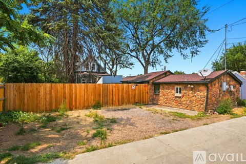 A wooden fence in front of a tan building with a tree branch hanging over it.