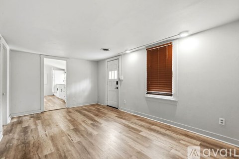 A room with wooden flooring and a doorway leading to another room.