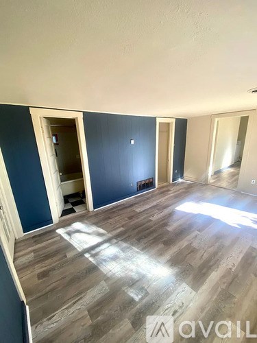A room with wooden flooring and a large mirror on the wall.