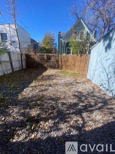 A backyard with a gravel ground and a fence.