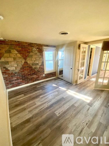 A room with wooden floors and a brick wall.