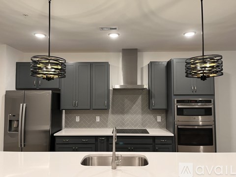 A modern kitchen with a stainless steel refrigerator and a range hood.