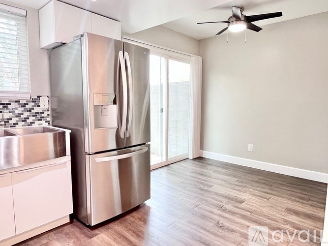 A modern kitchen with a stainless steel refrigerator and a ceiling fan.