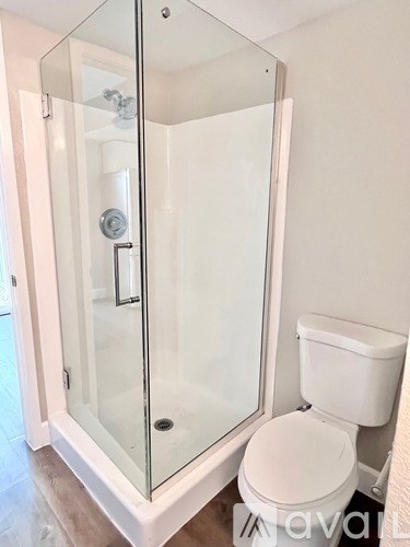 A white toilet sits next to a glass shower stall.