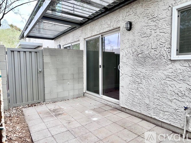 A patio area with a sliding glass door and a grey fence.